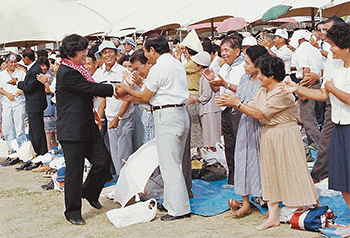 徳之島病院竣工式で喜びに沸く島民と握手を交わす徳田・前理事長（前列左）