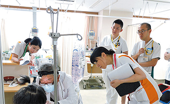 回診で患者さんの口腔内や嚥下の状態を確認する三宅部長（左から2人目）や須釜副主任（その右）ら
