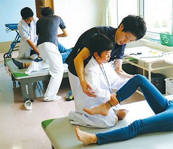 理学療法士に教わりながら患者さん役の親にリハビリを施す