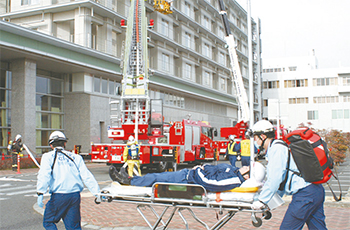 救急車に患者さん役を運ぶ救急隊員