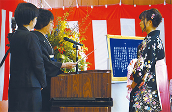 鈴木校長（左から2人目）が一人ひとりに卒業証書を手渡す