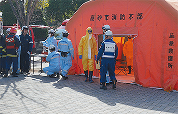 負傷者役を待つ新保院長（黄色の防護服を着用した中央の人物）